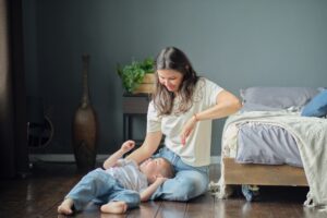Son lies on her mother's lap, they smile. Family composition. Motherhood, maternity leave concept